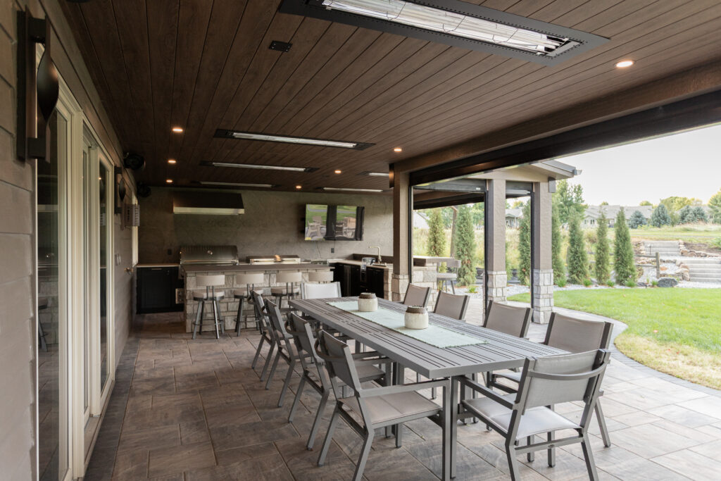 custom covered patio ideas - outdoor kitchen with heaters, motorized screens, and plenty of seating space