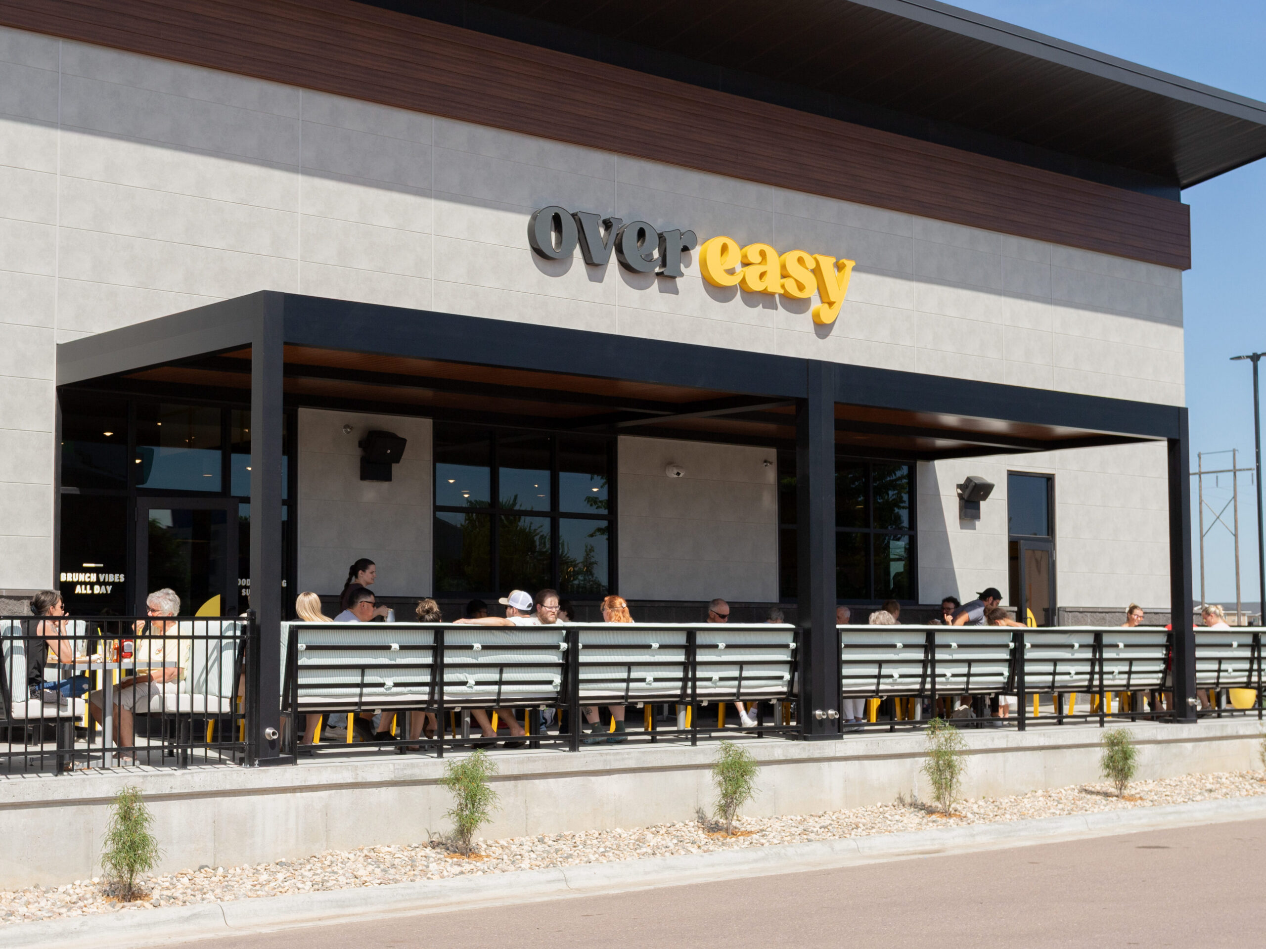 Black and wood grain commercial patio pergola creates a shaded space for restaurant patio