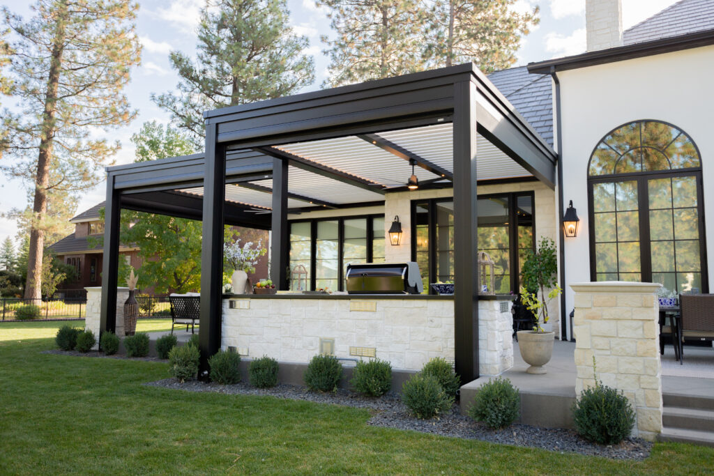 A black and white custom motorized pergola covers the patio, outdoor kitchen, and seating space.