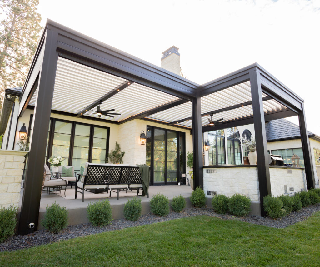 large white and black motorized louvered pergola covers a concrete patio for shade and weather protection.